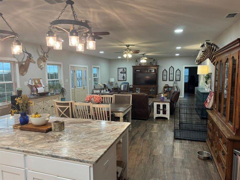 Kitchen featuring dark wood-type flooring, recessed lighting, white cabinetry, decorative light fixtures, and open floor plan Kitchen featuring dark wood-type flooring, recessed lighting, white cabinetry, decorative light fixtures, and open floor plan
