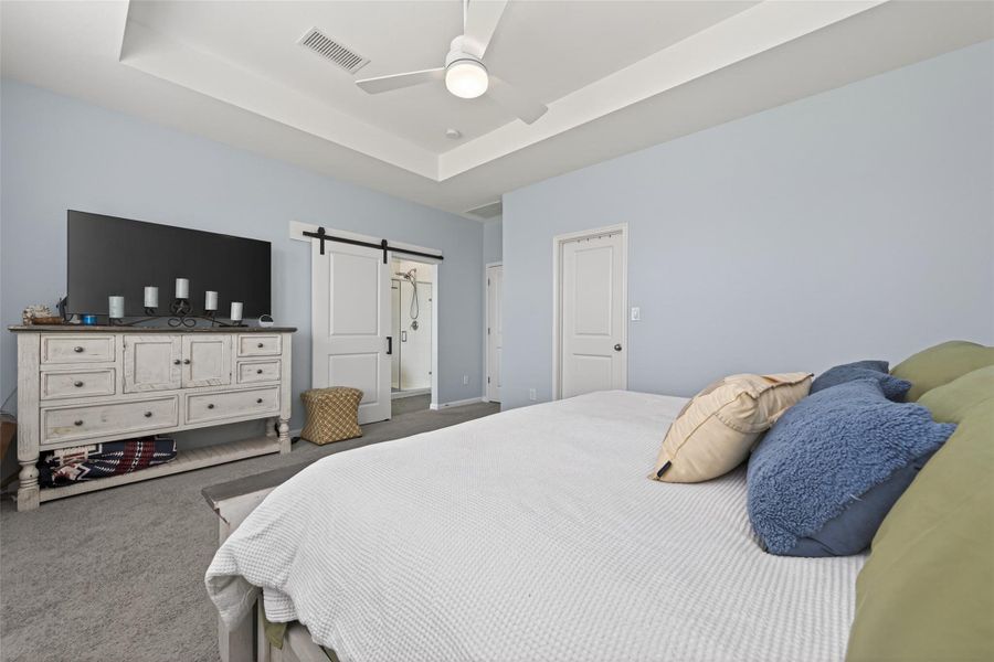 Primary bedroom offering a tray ceiling and access to the ensuite bath