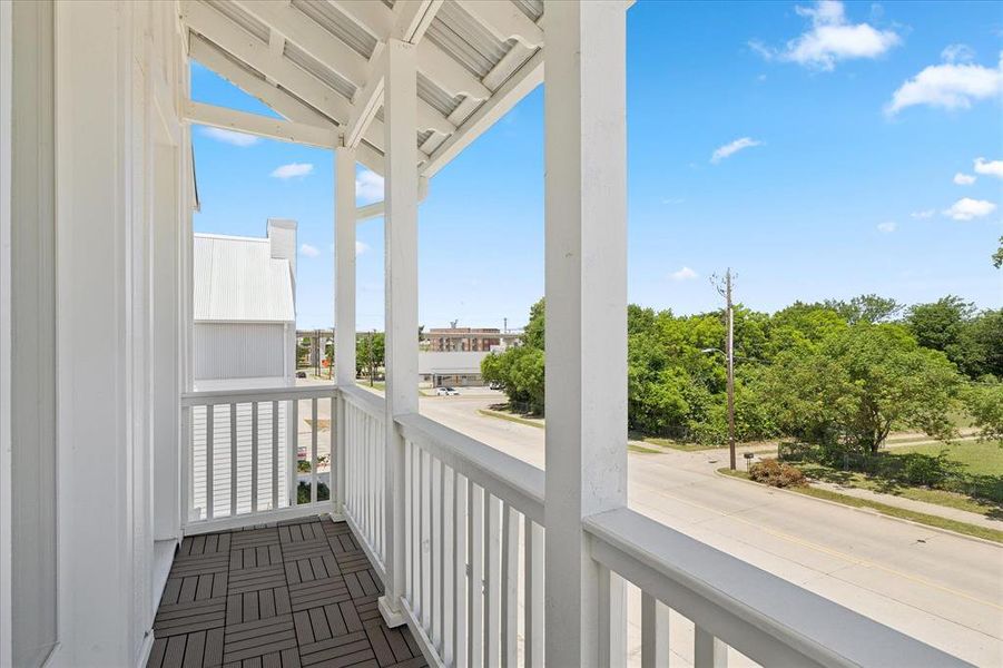 Private balcony featuring dark wood-finish flooring, white shiplap siding, and white railings
