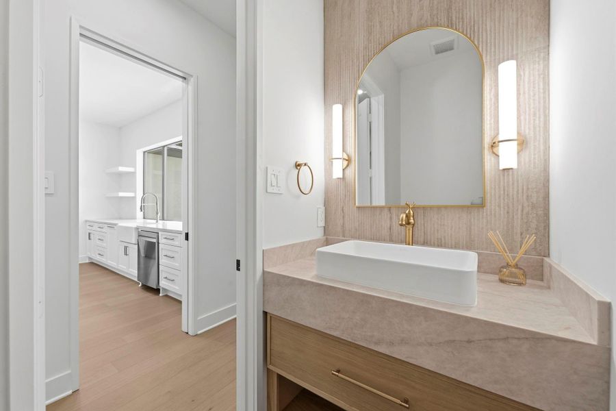 Half bath with a DESIGNER ribbon-wood FEATURE wall located right off the laundry room, kitchen, and scullery.