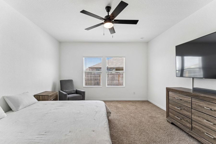 A well-lit primary bedroom with plush carpeting, offering a comfortable and serene retreat.