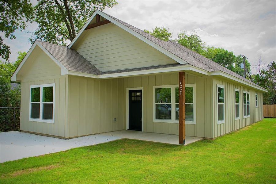 Rear view of property featuring roof with shingles, board and batten siding, and a patio
