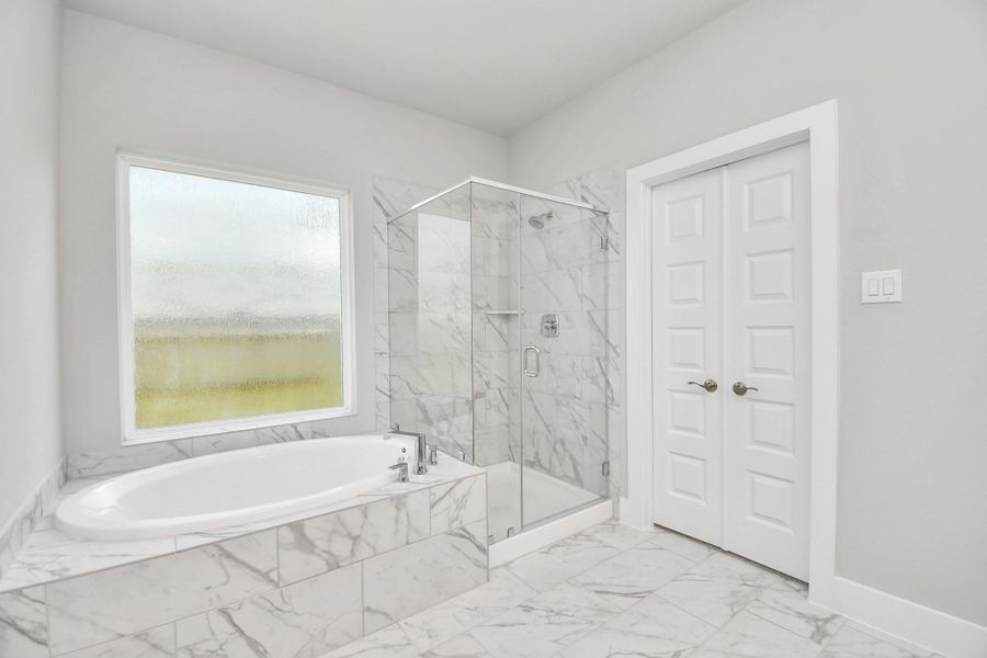 This additional view of the primary bath features a walk-in shower with the tile surround and separate garden tub perfect for soaking after a long day. Sample photo of completed home with similar floor plan. Actual colors and selections may vary.