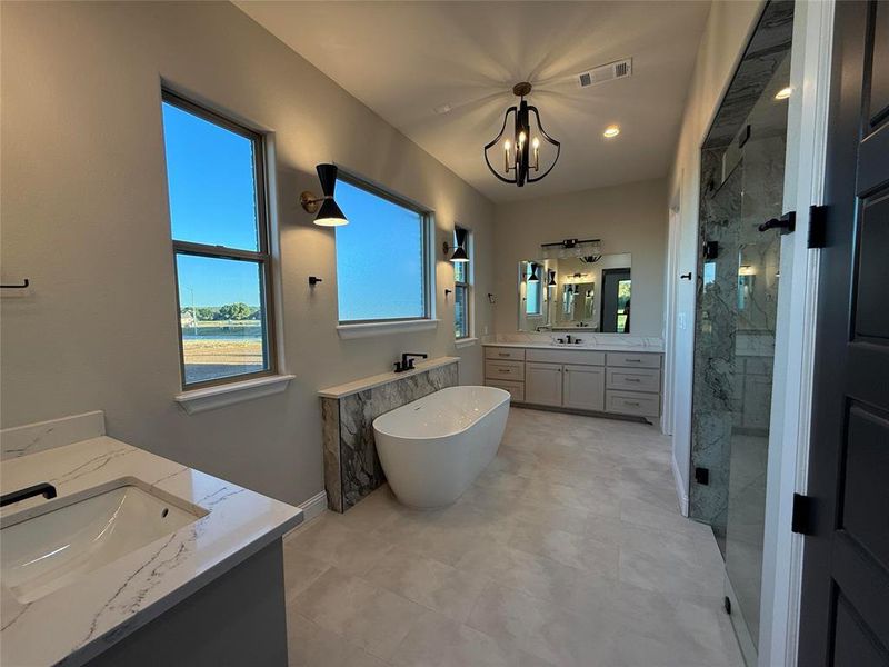 Full bath with two vanities, a marble finish shower, a freestanding bath, plenty of natural light, and recessed lighting Full bath with two vanities, a marble finish shower, a freestanding bath, plenty of natural light, and recessed lighting