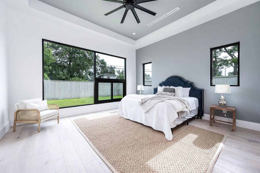 Primary bedroom with a large-format custom window showcasing abundant natural light and backyard views, creating a bright and spacious retreat.
