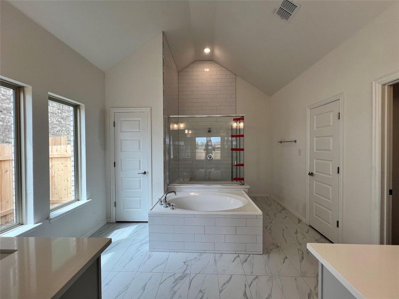 Bathroom with marble look tiles, lofted ceiling, a bath, healthy amount of natural light, and vanity Bathroom with marble look tiles, lofted ceiling, a bath, healthy amount of natural light, and vanity
