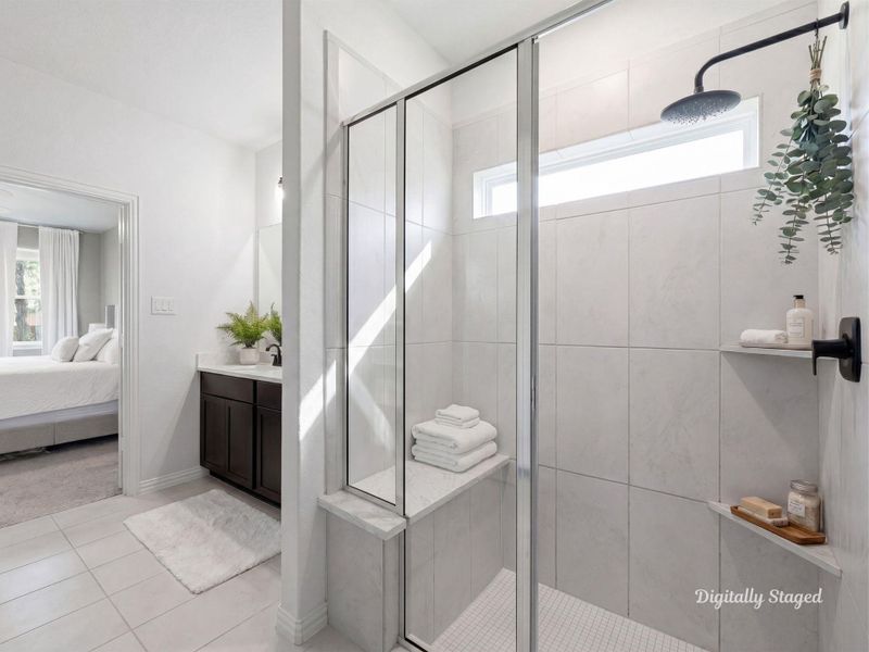 Walk-in shower featuring a full tile surround, built-in bench, and rainfall-style showerhead beneath a transom window for natural light. Conveniently positioned just off the primary bedroom. This photo has been digitally staged to illustrate the possibilities of the home's aesthetic and potential design. Some furnishings and décor shown are for visual inspiration.