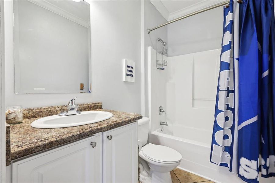 Full bathroom featuring vanity, toilet, crown molding, tile patterned floors, and shower / bath combo with shower curtain