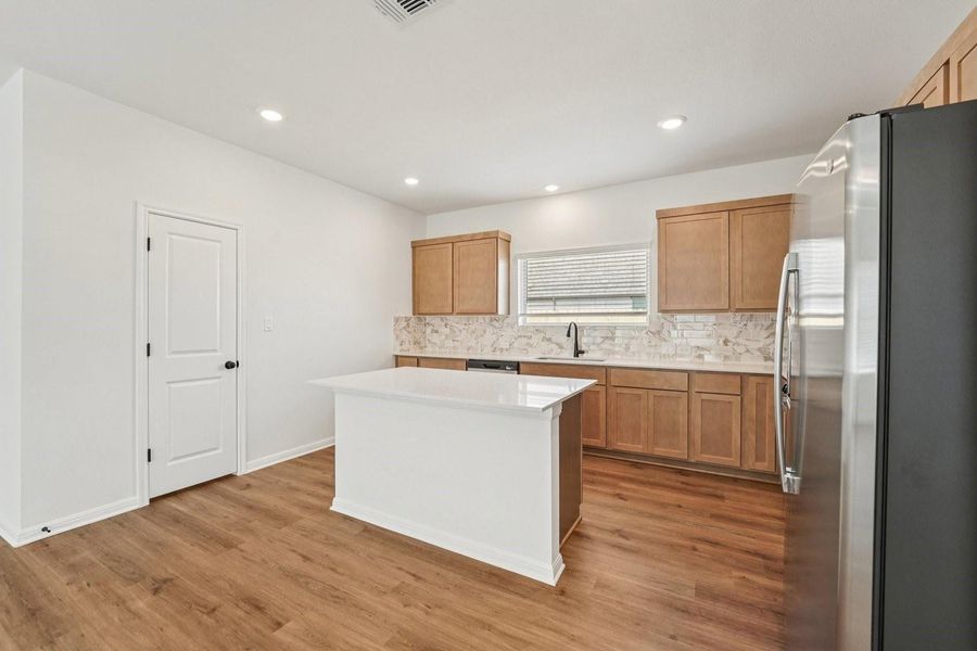 A well-appointed kitchen features a central island, rich cabinetry, and sleek appliances, all set on attractive wood flooring. A well-appointed kitchen features a central island, rich cabinetry, and sleek appliances, all set on attractive wood flooring.
