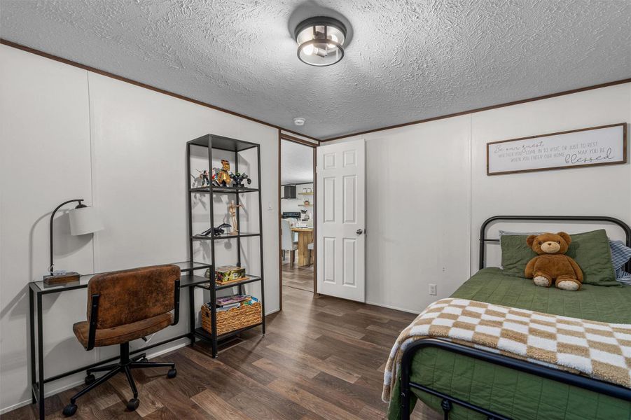Bedroom with dark wood-style floors, crown molding, and a textured ceiling