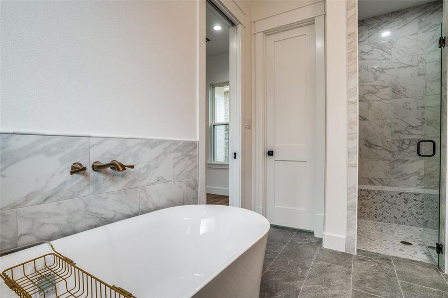 Bathroom featuring tile walls and shower with separate bathtub