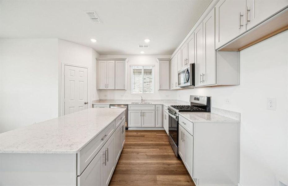 Large island overlooking gathering room and dining areas