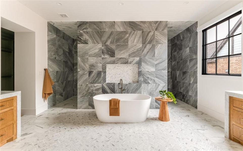 Bathroom with vanity, a freestanding bath, marble look tile flooring, tile walls, and walk in shower