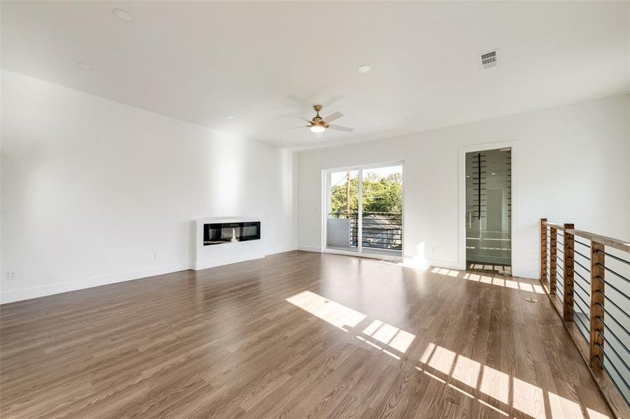 Unfurnished living room featuring wood finished floors, a glass covered fireplace, ceiling fan, and recessed lighting Unfurnished living room featuring wood finished floors, a glass covered fireplace, ceiling fan, and recessed lighting