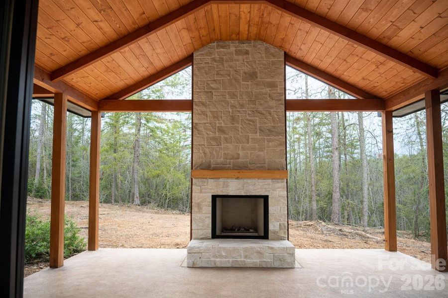 Private outdoor screened deck featuring vaulted tongue-and-groove ceilings and a wood-burning fireplace.