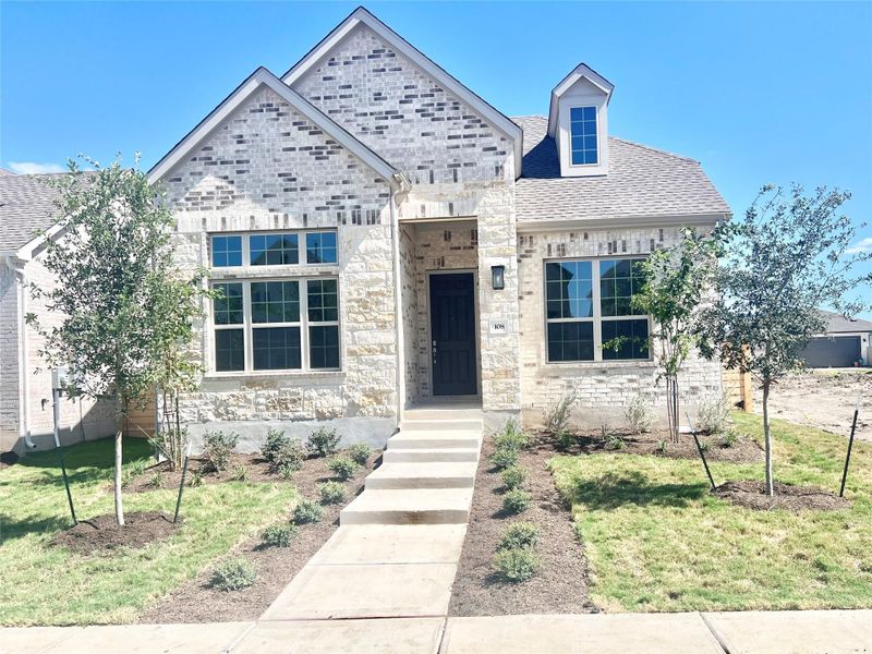 View of front of property featuring stone siding, a shingled roof, and a front yard