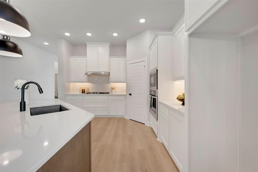 Kitchen featuring white cabinets, recessed lighting, light wood-style floors, stainless steel appliances, and light stone counters