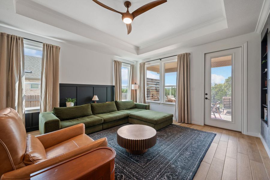 Living room featuring a tray ceiling, wood finished floors, ornamental molding, and a ceiling fan Living room featuring a tray ceiling, wood finished floors, ornamental molding, and a ceiling fan