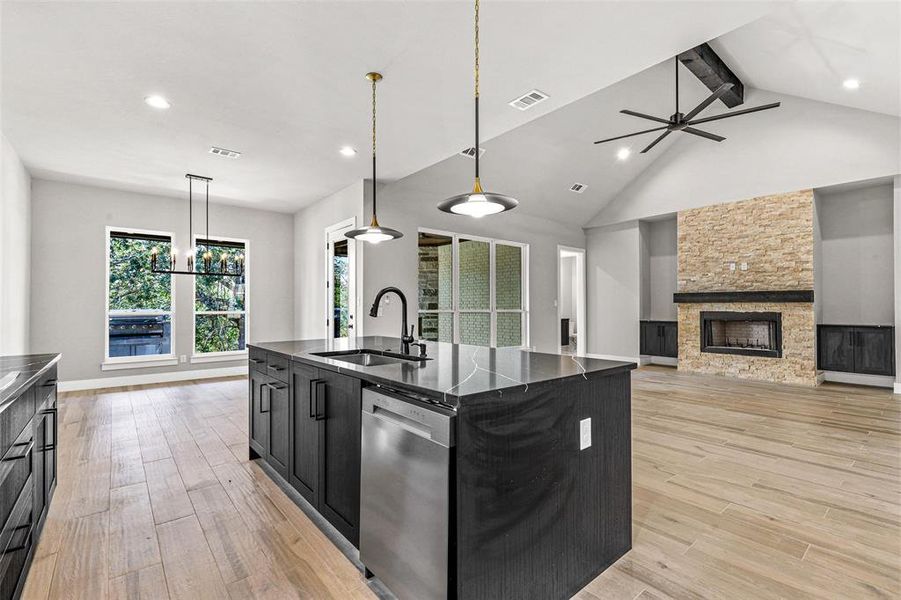 Kitchen with a center island with sink, sink, beam ceiling, stainless steel dishwasher, and light hardwood / wood-style flooring