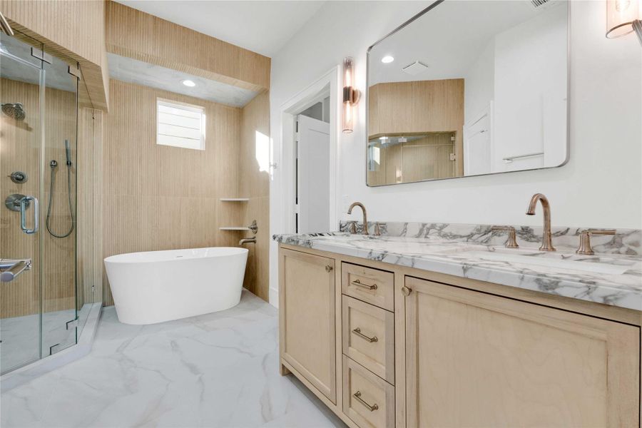 A beautifully designed primary bathroom with custom-built vanities, premium tilework, and a modern freestanding soaking tub.
