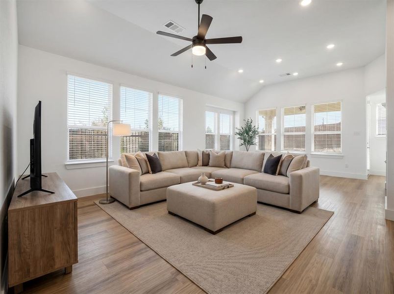 This spacious living area features vaulted ceilings, recessed lighting, and a ceiling fan