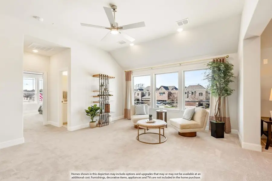 Bright sitting room with vaulted ceiling, ceiling fan, carpet flooring, and large windows overlooking neighborhood homes.