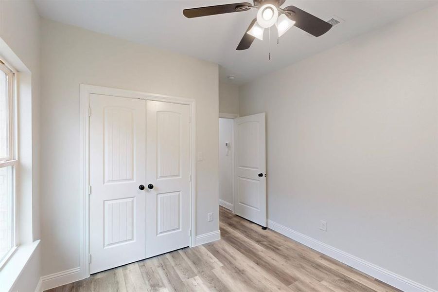 Unfurnished bedroom with ceiling fan, light wood-type flooring, and a closet