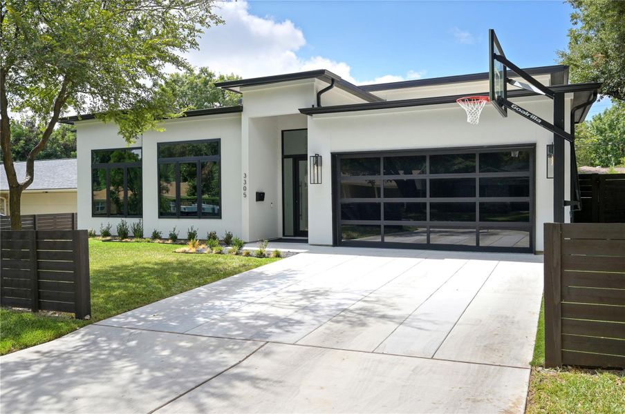 Modern home featuring concrete driveway, stucco siding, an attached garage, and a front yard
