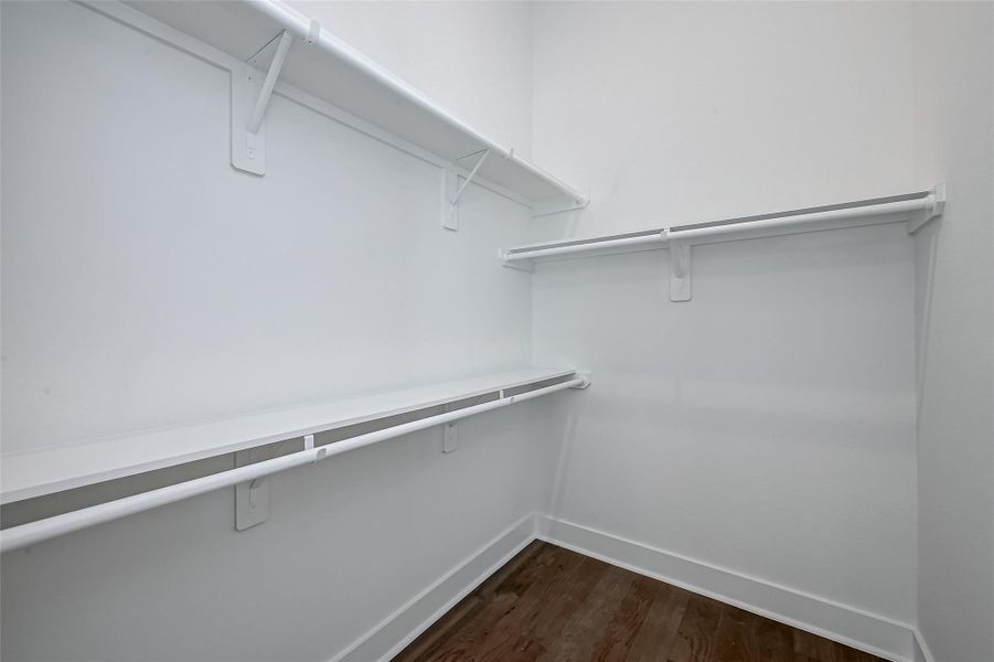 Ample storage space awaits in this generous walk-in closet. Dual-height hanging rods and shelving keep everything organized, while crisp white finishes reflect the home’s modern style.