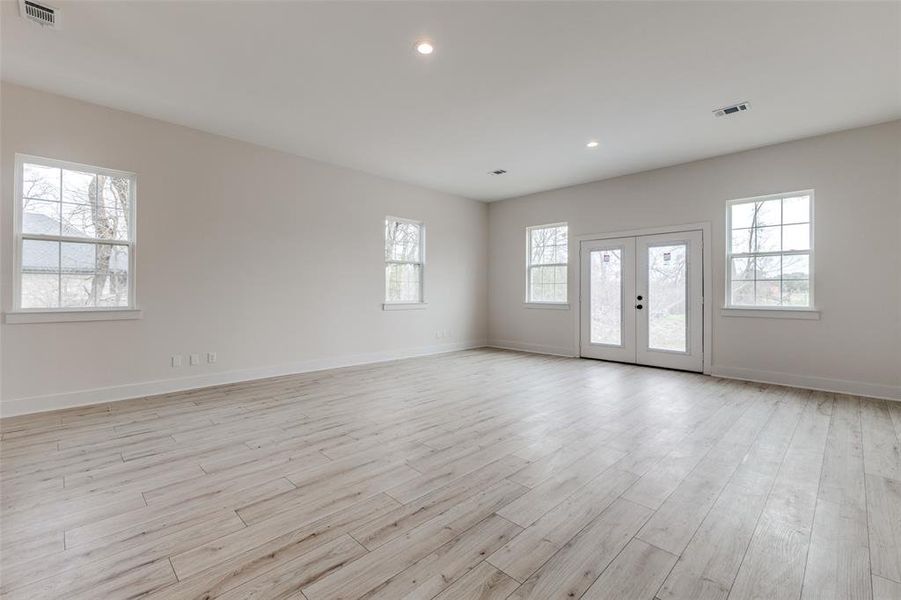 Unfurnished room featuring light wood-type flooring, visible vents, baseboards, and french doors