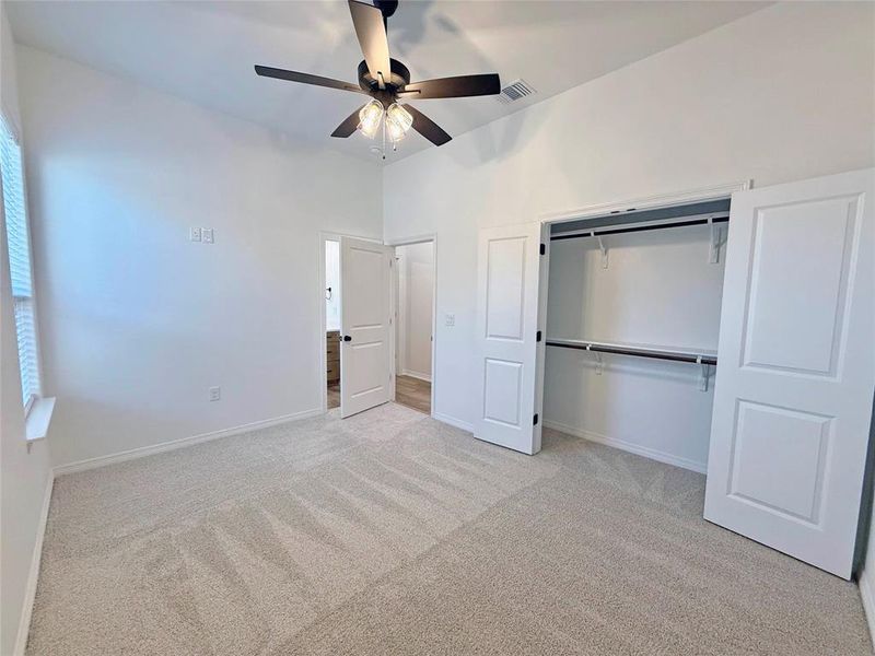 Unfurnished bedroom featuring light colored carpet, a ceiling fan, and a closet