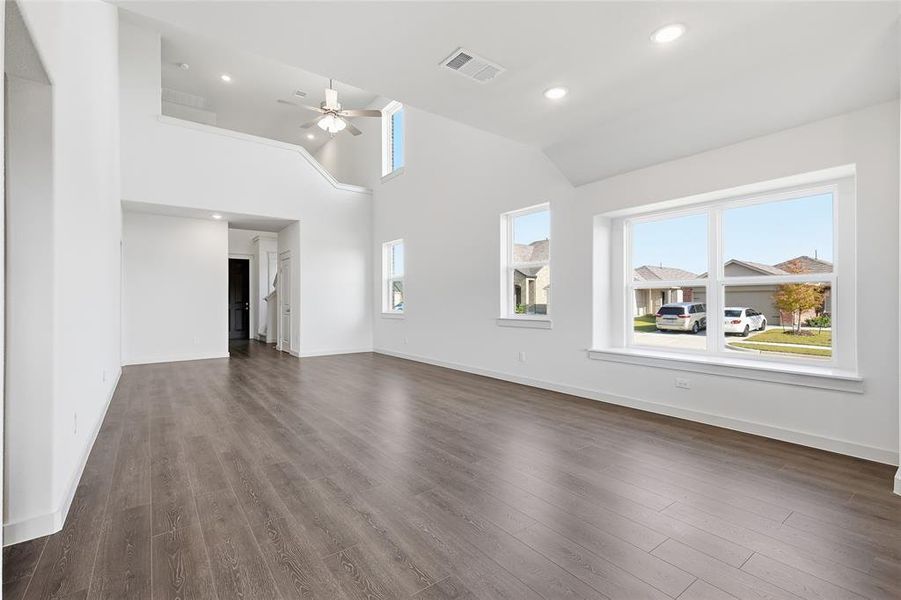 Unfurnished living room featuring dark wood-style floors, high vaulted ceiling, ceiling fan, and recessed lighting Unfurnished living room featuring dark wood-style floors, high vaulted ceiling, ceiling fan, and recessed lighting