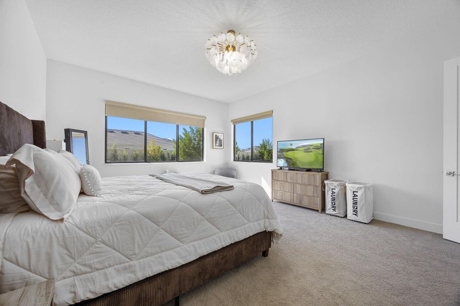 Carpeted bedroom with baseboards and a chandelier