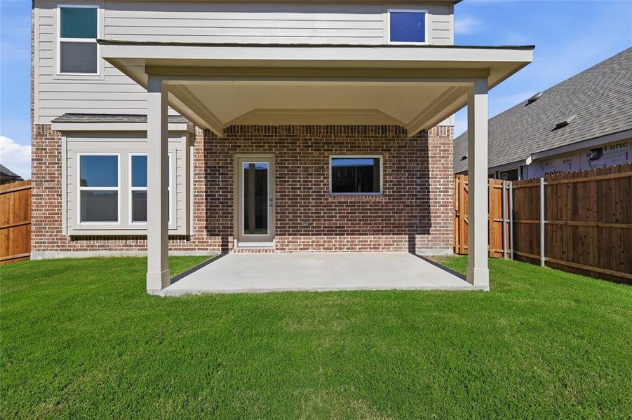 Covered patio with a concrete slab, brick exterior, siding accents, and a manicured lawn