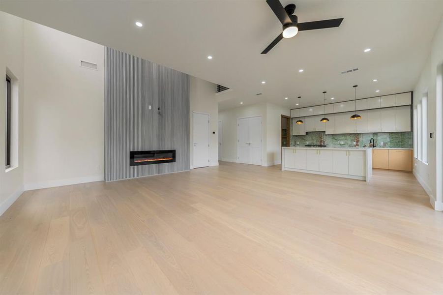 Family room with a fireplace, a ceiling fan, light wood finished floors, and recessed lighting
