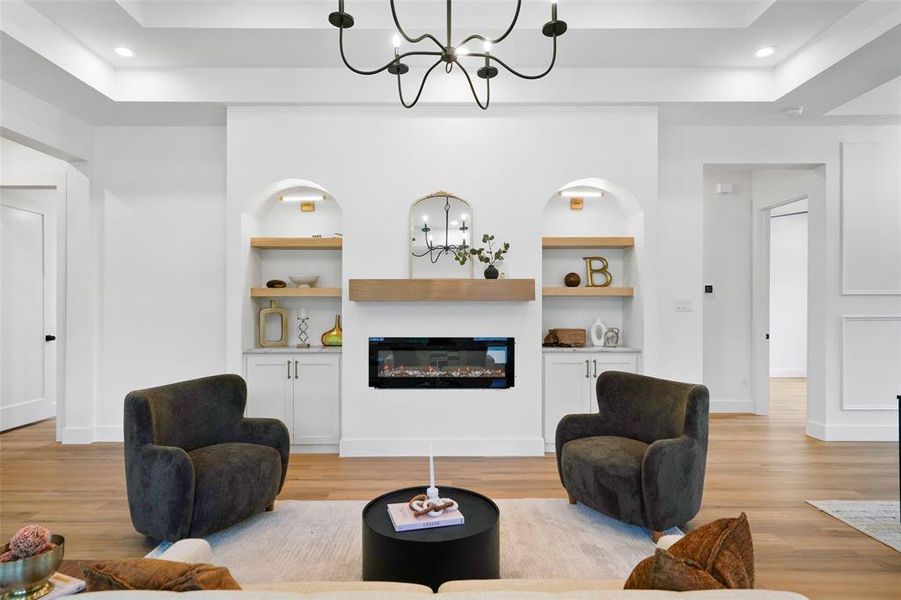 Central fireplace feature wall with an electric fireplace, wood mantel, and built-in arched display niches