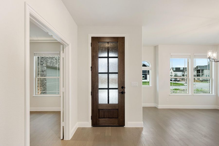 Home entryway with dark wood front door featuring glass panels and light hardwood floors Home entryway with dark wood front door featuring glass panels and light hardwood floors