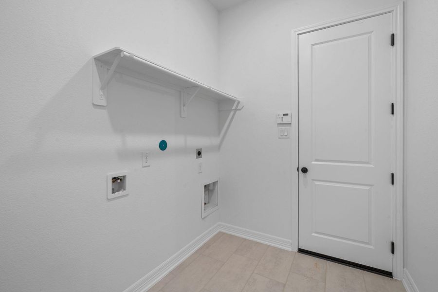Functional utility room with shelving and convenient laundry hookups.