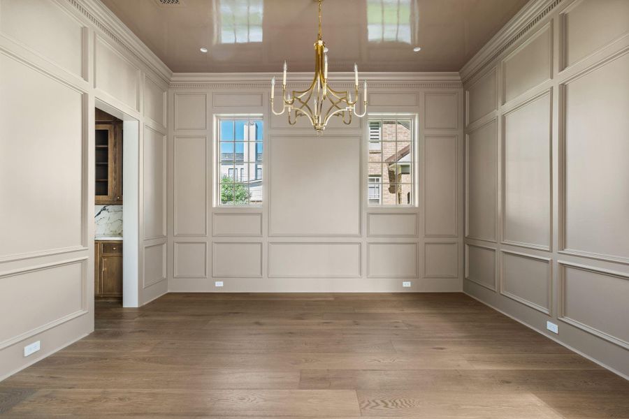 The formal dining room showcases sophisticated wall paneling, wide-plank wire brushed wood flooring, and a statement chandelier, creating an elegant setting for entertaining and holiday gatherings. The formal dining room showcases sophisticated wall paneling, wide-plank wire brushed wood flooring, and a statement chandelier, creating an elegant setting for entertaining and holiday gatherings.