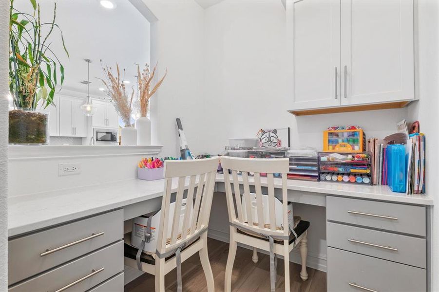 L-shaped built-in desk with a light-colored countertop and grey drawer bases