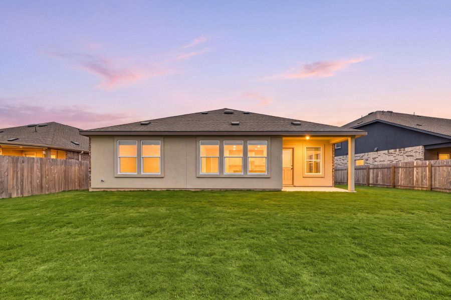 A spacious backyard with vibrant green grass and an inviting patio awaits outdoor enjoyment.
