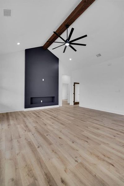 Unfurnished living room with ceiling fan, light hardwood / wood-style flooring, high vaulted ceiling, and beamed ceiling