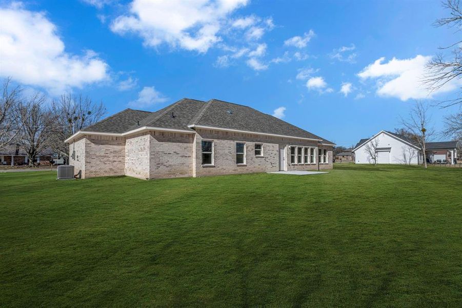 Rear view of house featuring central AC unit and a lawn