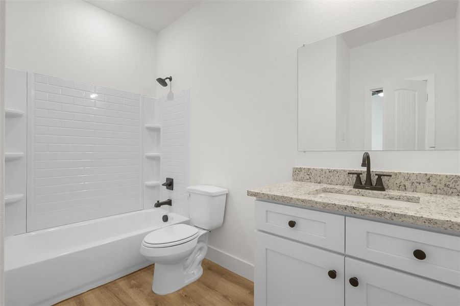 Full bathroom with wood-type flooring, toilet, vanity, and shower / washtub combination