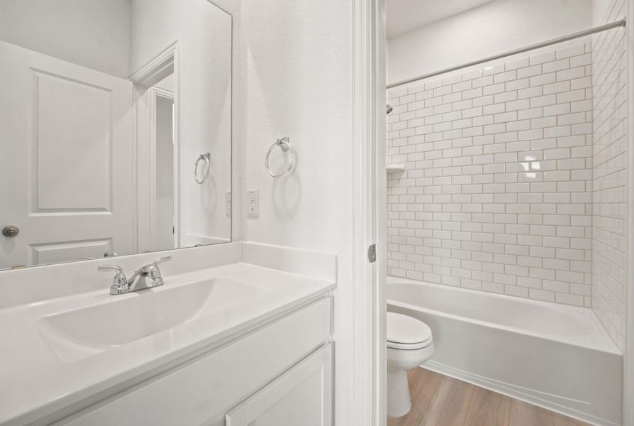Crisp subway tile lines the shower surround adjacent to a clean white vanity.