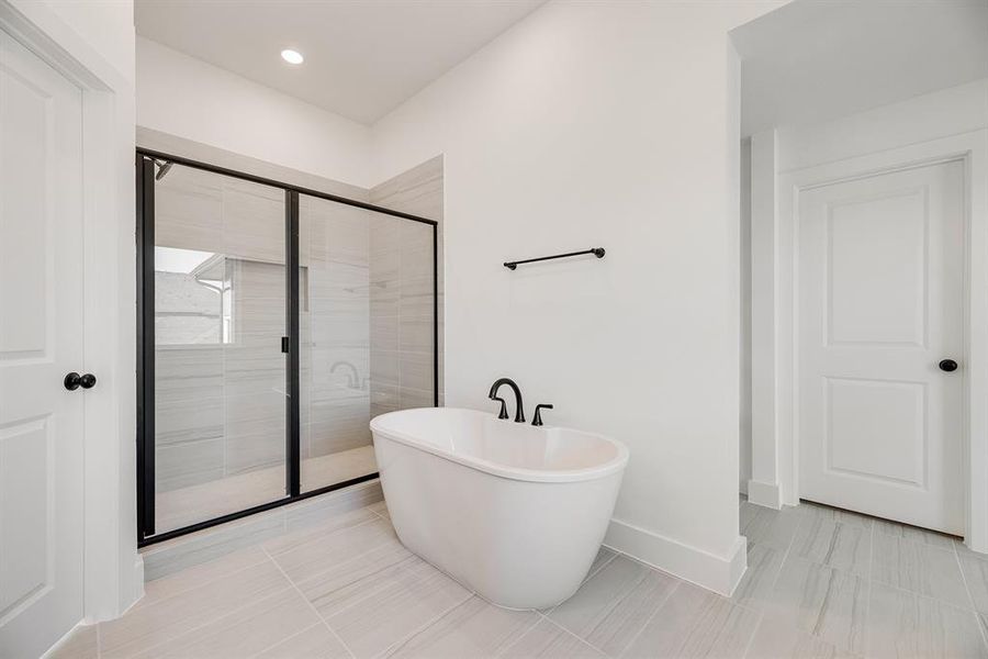 Bathroom with a soaking tub, a shower stall, light tile patterned floors, and recessed lighting