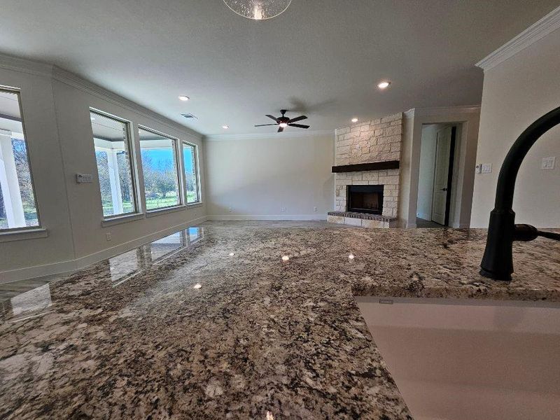 Unfurnished living room with ornamental molding, a stone fireplace, recessed lighting, and a ceiling fan
