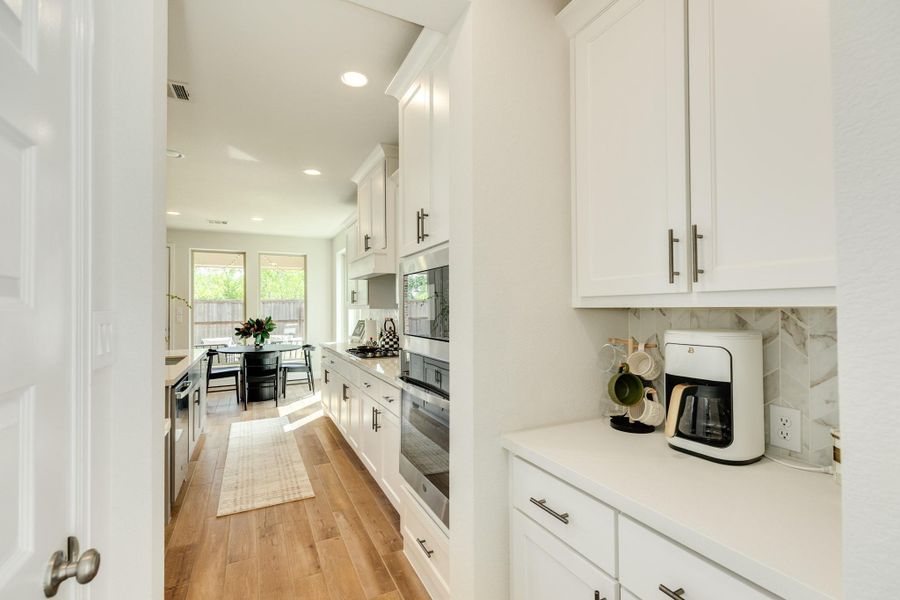 Butler's pantry area featuring modern backsplash design coordinated with the main kitchen, elegant quartz countertops, and ample additional storage. Butler's pantry area featuring modern backsplash design coordinated with the main kitchen, elegant quartz countertops, and ample additional storage.