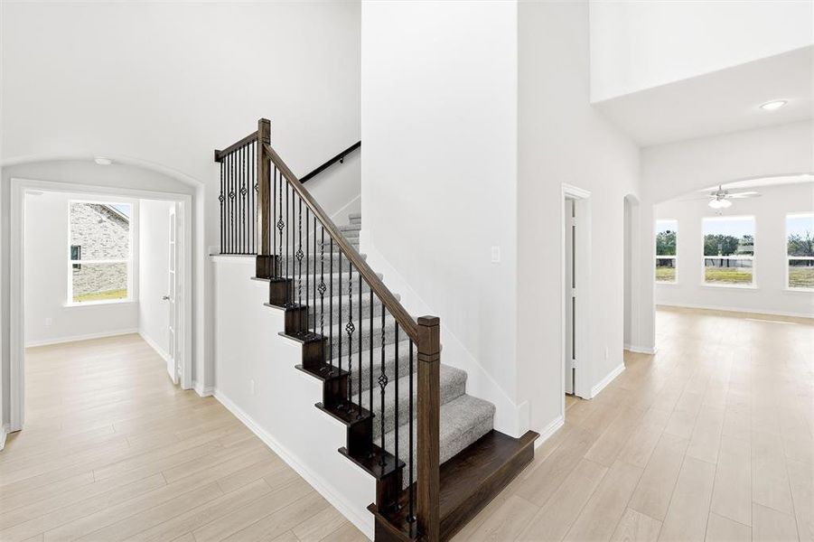 Staircase featuring arched walkways, healthy amount of natural light, wood finished floors, and a towering ceiling
