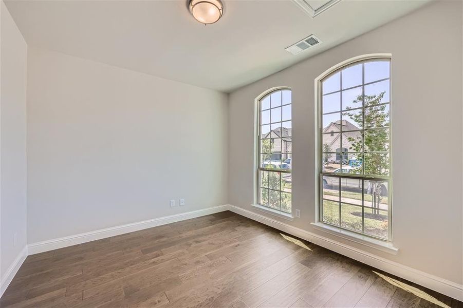 Empty room featuring dark hardwood / wood-style flooring and plenty of natural light